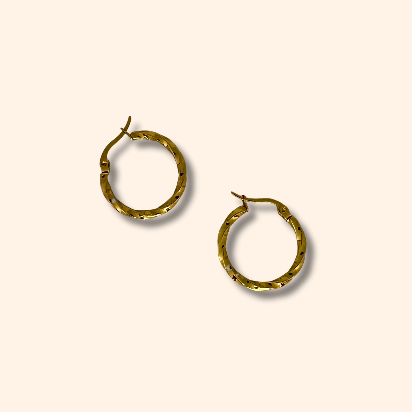 Two Gold Small Spiral Hoop Earrings by Roots Jewellery, featuring versatile clasp closures, rest elegantly on a light beige background.