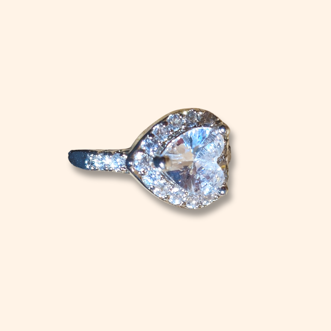 A heart-shaped Luxe Heart Zircon ear cuff by Roots Jewellery, elegantly set on a smooth band and adorned with a halo of zircons, displayed against a plain background.