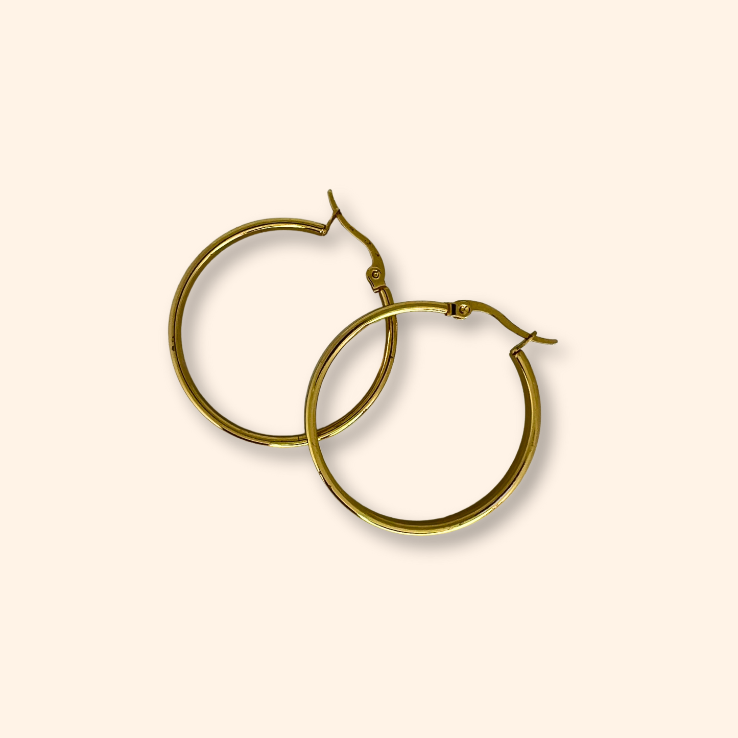 Discover the Gold Smooth Hoop Earrings from Roots Jewellery, set against a light beige backdrop. Meticulously crafted, these earrings boast a timeless elegance that effortlessly surpasses fleeting trends, establishing them as an essential piece in any jewelry collection.