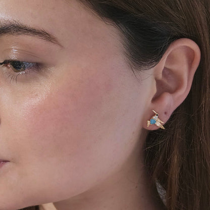 Roots Jewellery's Gold and Blue Bird Earrings grace a beige backdrop, ideal for those who appreciate nature-inspired elegance with a hint of animal charm.