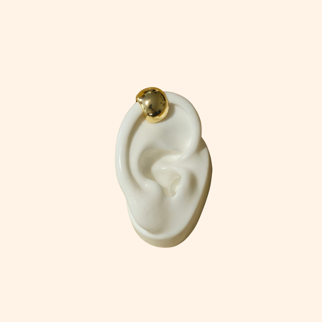 The Dome Shape Ear Cuff by Roots Jewellery features a shiny, metallic open-ended design, elegantly highlighting its dome style against a plain backdrop. This versatile accessory is perfect for adding an edgy touch to any style, resembling a sleek stainless steel ear cuff.