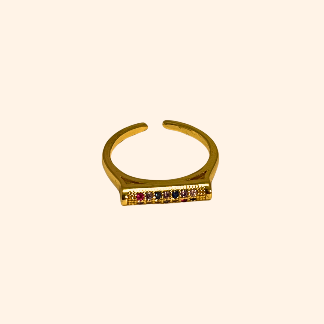 Introducing the Rainbow Signet Gold Ring by Roots Jewellery: an open-ended gold ring with a rectangular top adorned with three small rainbow-colored zircons, ideal for the fashion-forward individual.