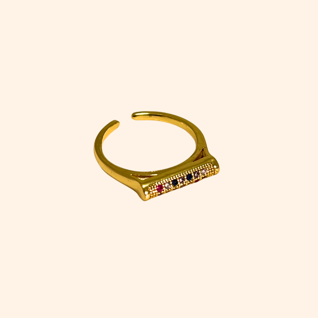 Introducing the Rainbow Signet Gold Ring by Roots Jewellery: an open-ended gold ring with a rectangular top adorned with three small rainbow-colored zircons, ideal for the fashion-forward individual.