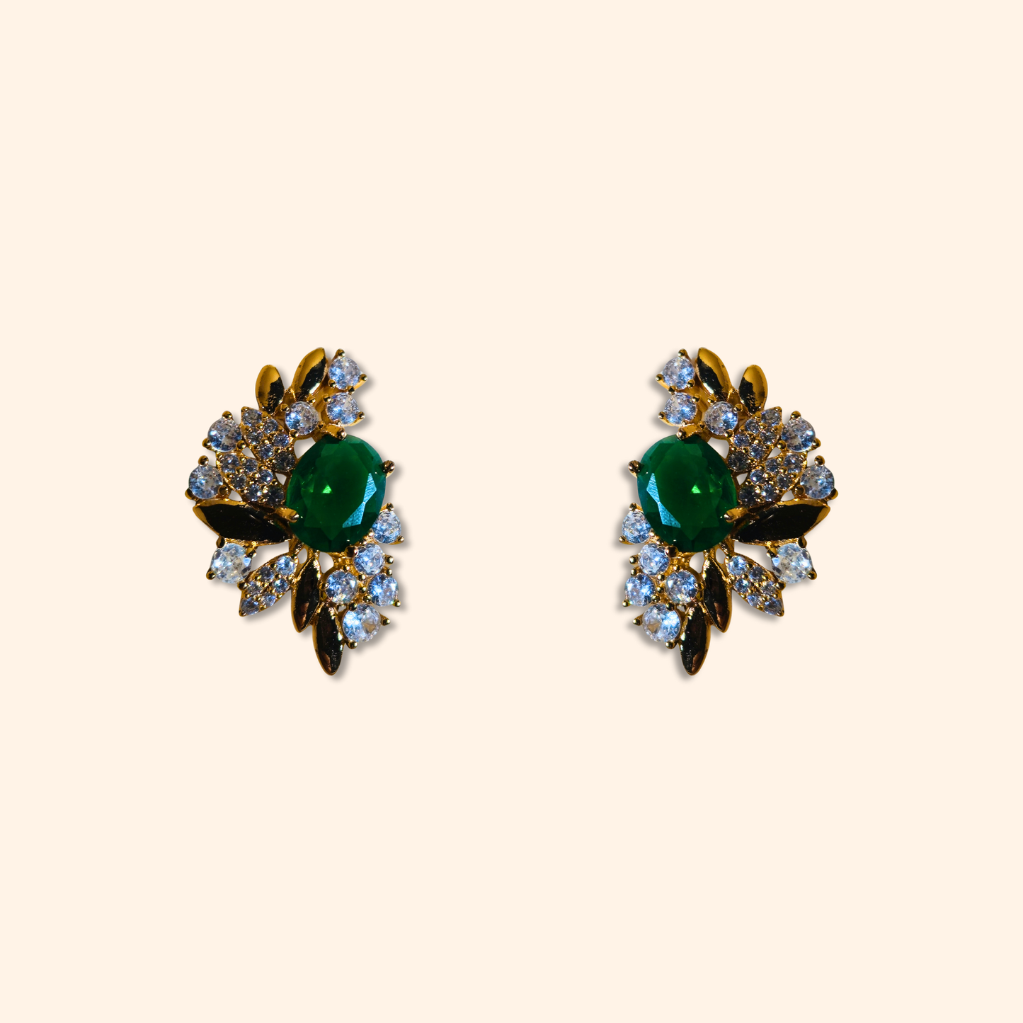 Behold the Emerald Floral Gold Earrings by Roots Jewellery, a stunning pair of vintage-inspired earrings featuring intricate floral designs with emerald green central stones surrounded by cubic zirconia.