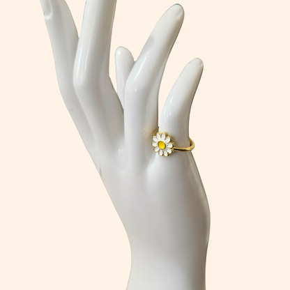 Explore the Daisy Gold Ring by Roots Jewellery, a striking piece adorned with a white and yellow daisy set against a sleek, neutral background.