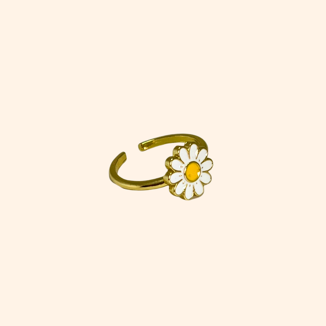 Explore the Daisy Gold Ring by Roots Jewellery, a striking piece adorned with a white and yellow daisy set against a sleek, neutral background.