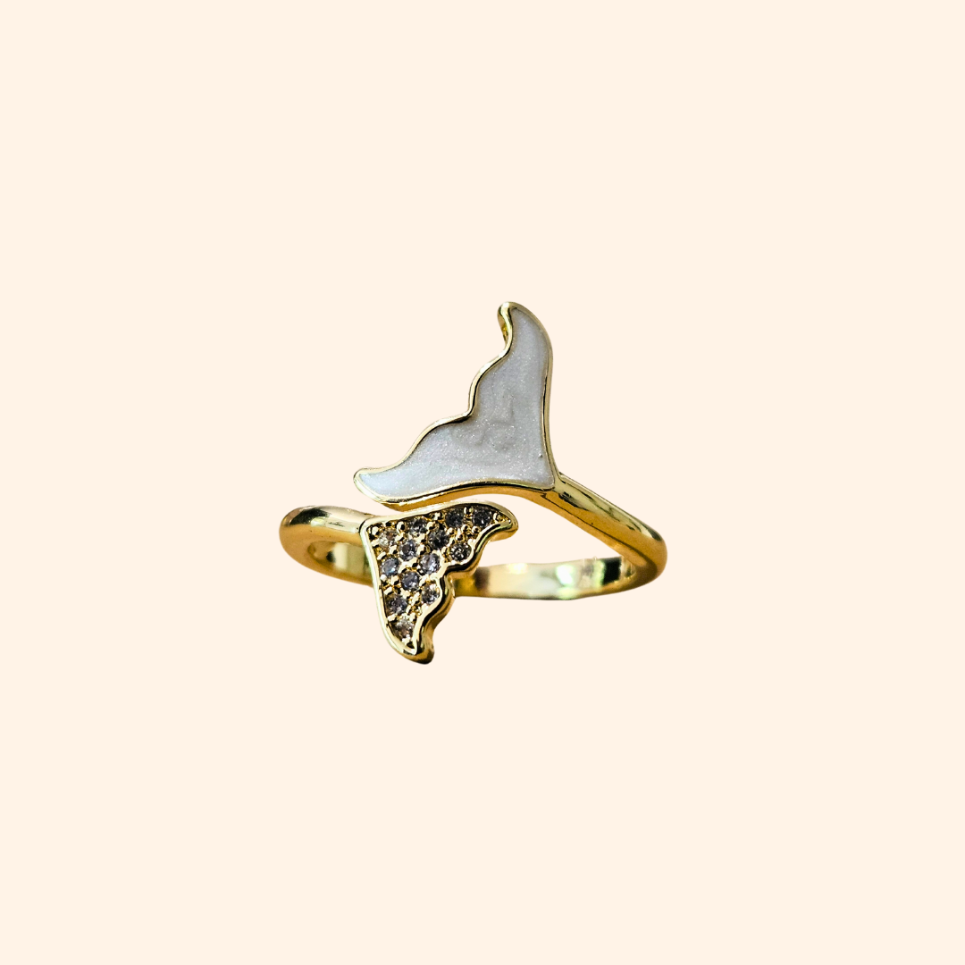 Introducing the Whale Tail - Gold & White Ring by Roots Jewellery, featuring an imaginative design reminiscent of a whimsical butterfly. This gold ring highlights one wing in pristine white and the other sparkling with twinkling gems, all enhanced by rhodium plating for an added touch of elegance. Set against a light backdrop, it beautifully captures the exquisite delicacy of nature's creations.