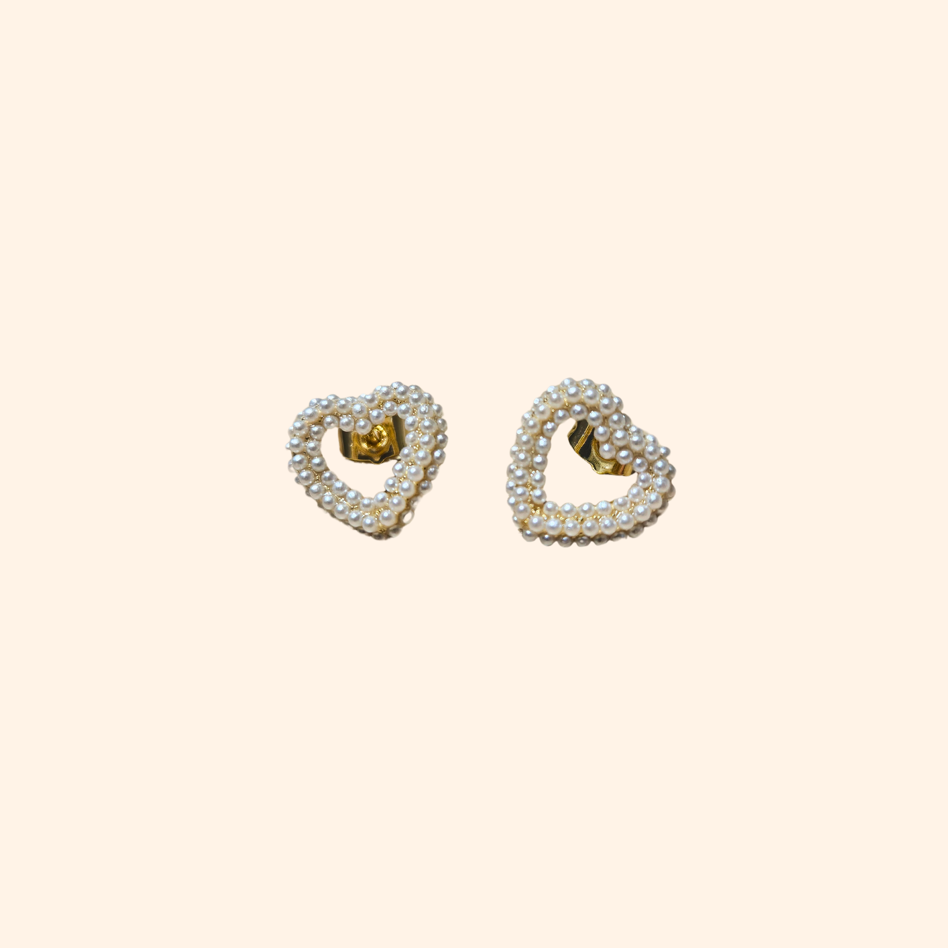 Roots Jewellery's Pearl Heart Gold Earrings showcase a timeless design, featuring delicate white pearls set against a minimalist background.