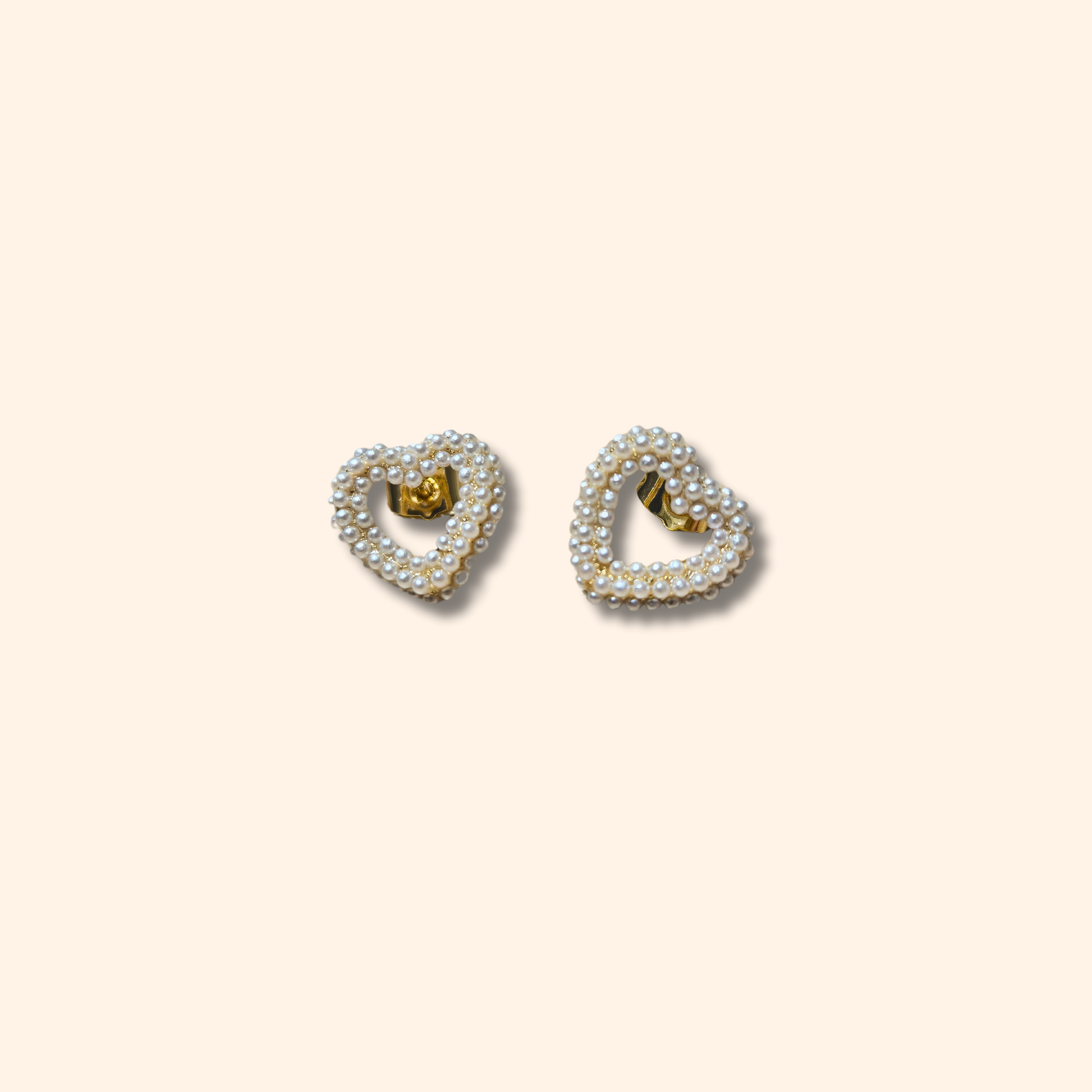 Roots Jewellery's Pearl Heart Gold Earrings showcase a timeless design, featuring delicate white pearls set against a minimalist background.