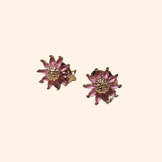 A sophisticated pair of Zirconia Margarita Earrings by Roots Jewellery, featuring pink petals and gold centers, set against a beige background and evoking the charm of Margarita blooms.