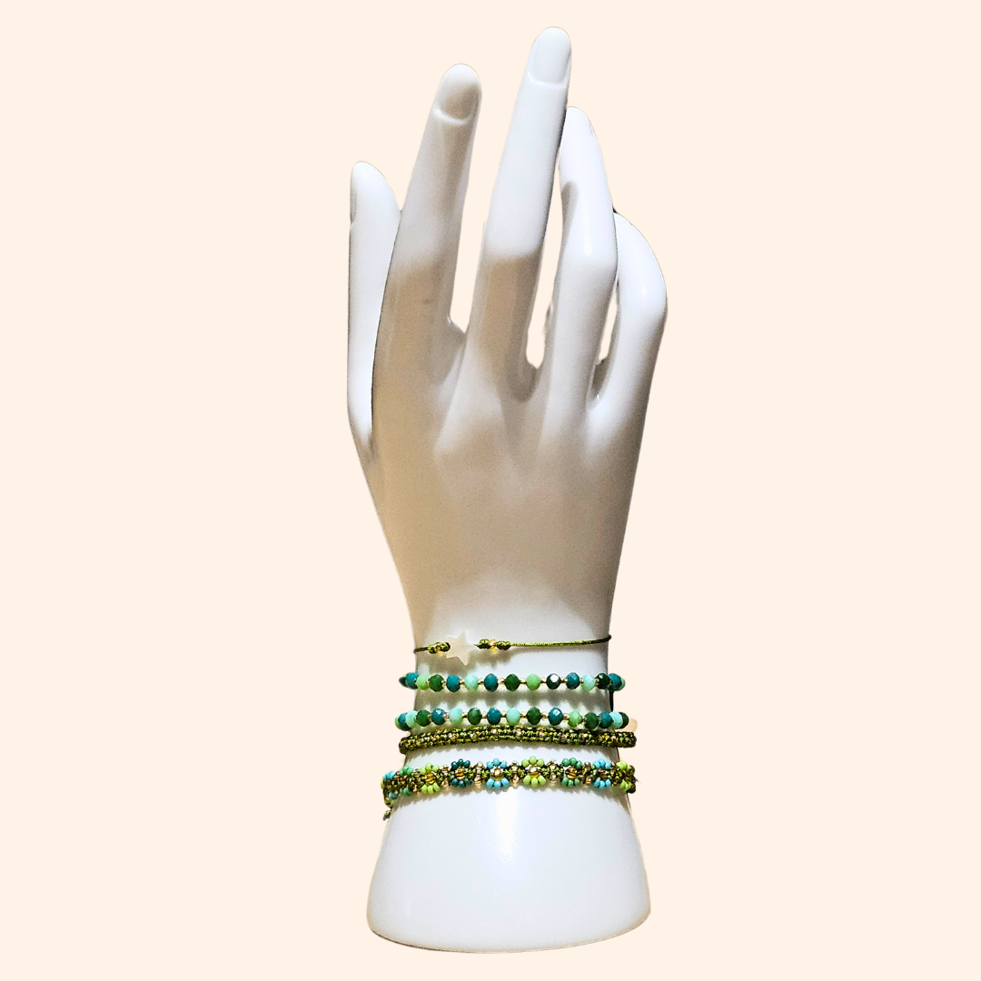 A forearm adorned with Roots Jewellery's Verdant Harmony 5-Set Bracelet, featuring handmade green and turquoise beads that highlight artisanal craftsmanship and a charming star pendant, with a hint of Bohemian style tattooed below.