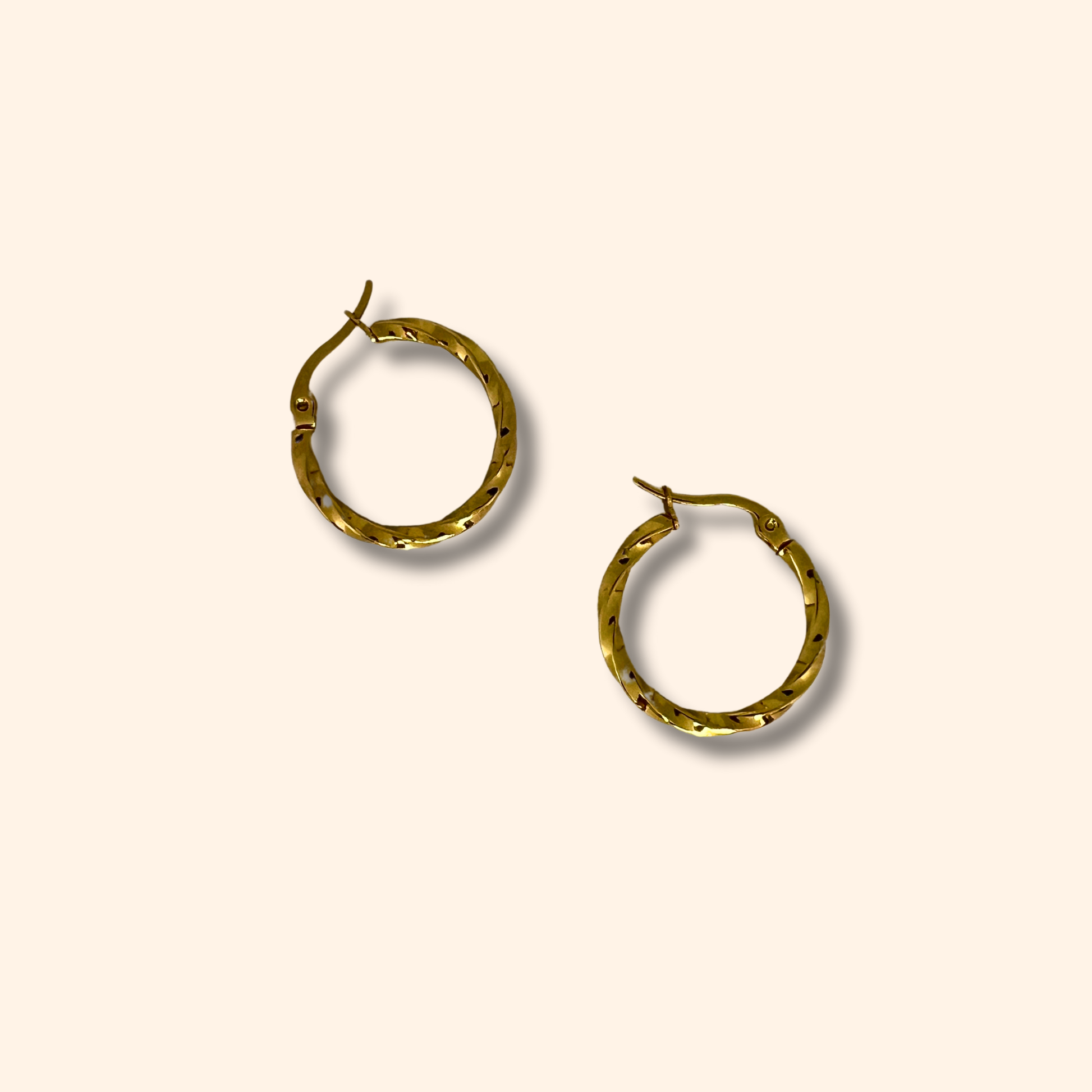 Two Gold Small Spiral Hoop Earrings by Roots Jewellery, featuring versatile clasp closures, rest elegantly on a light beige background.