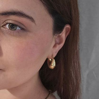 The Classic Gold Chunky Hoop Earrings by Roots Jewellery exude timeless elegance against a plain background.