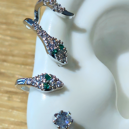 A mannequin ear displays the Sparkling Ivy Trio Earrings from Roots Jewellery, highlighting a vine-like design with a dangling earring at the top, a stud on the lobe, and a hoop adorned with zircon stones near the bottom.