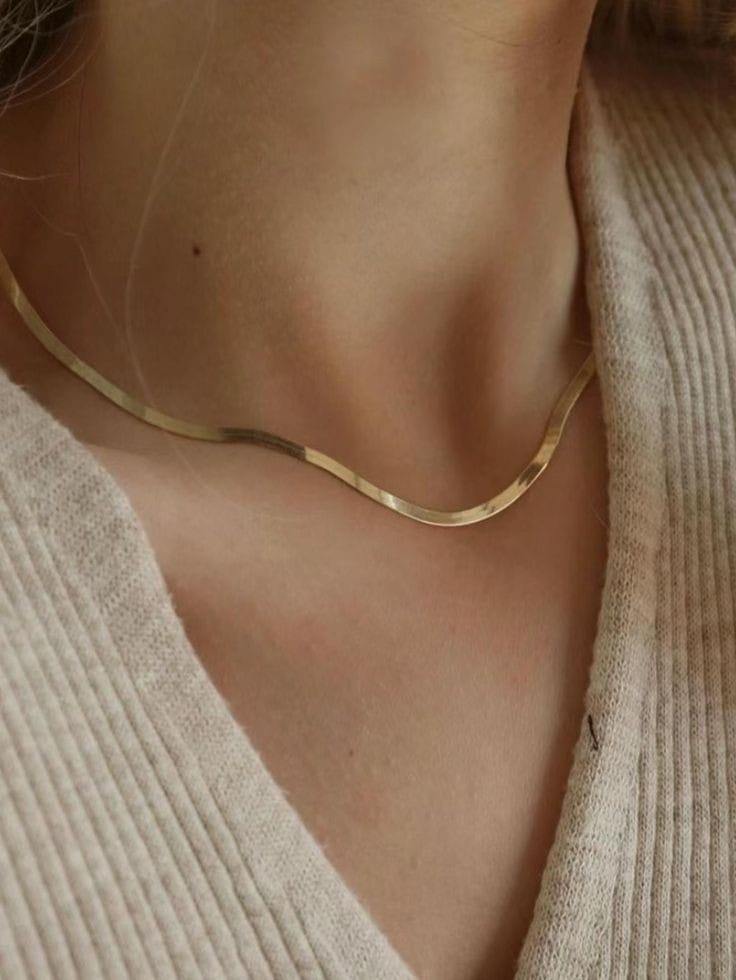 A woman showcases the refined design of the Roots Jewellery Gold Snake Chain Necklace over a light beige textured top.