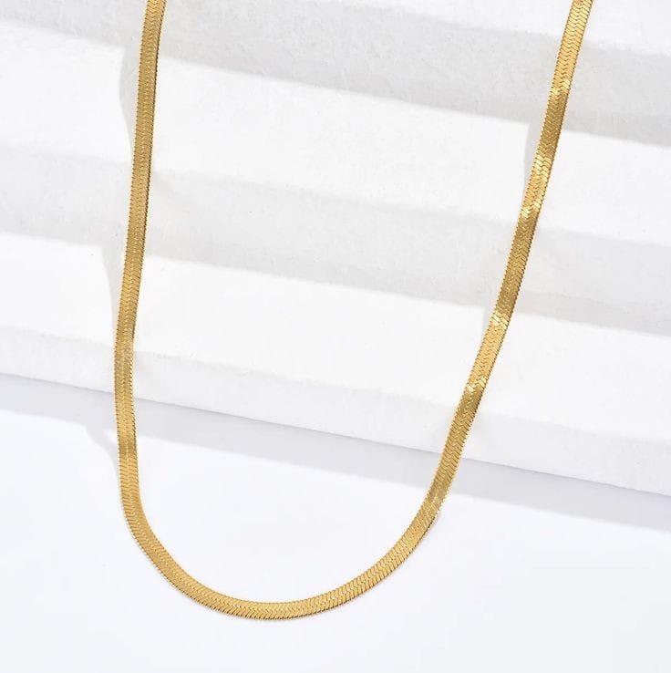 A woman showcases the refined design of the Roots Jewellery Gold Snake Chain Necklace over a light beige textured top.