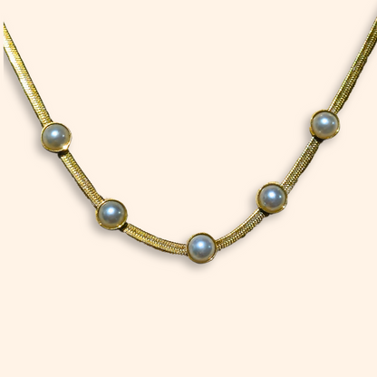 The Gold Necklace with Embedded Pearls by Roots Jewellery showcases five white pearls elegantly strung on a delicate gold-plated chain, complemented by matching pearl stud earrings, all set against a plain background.