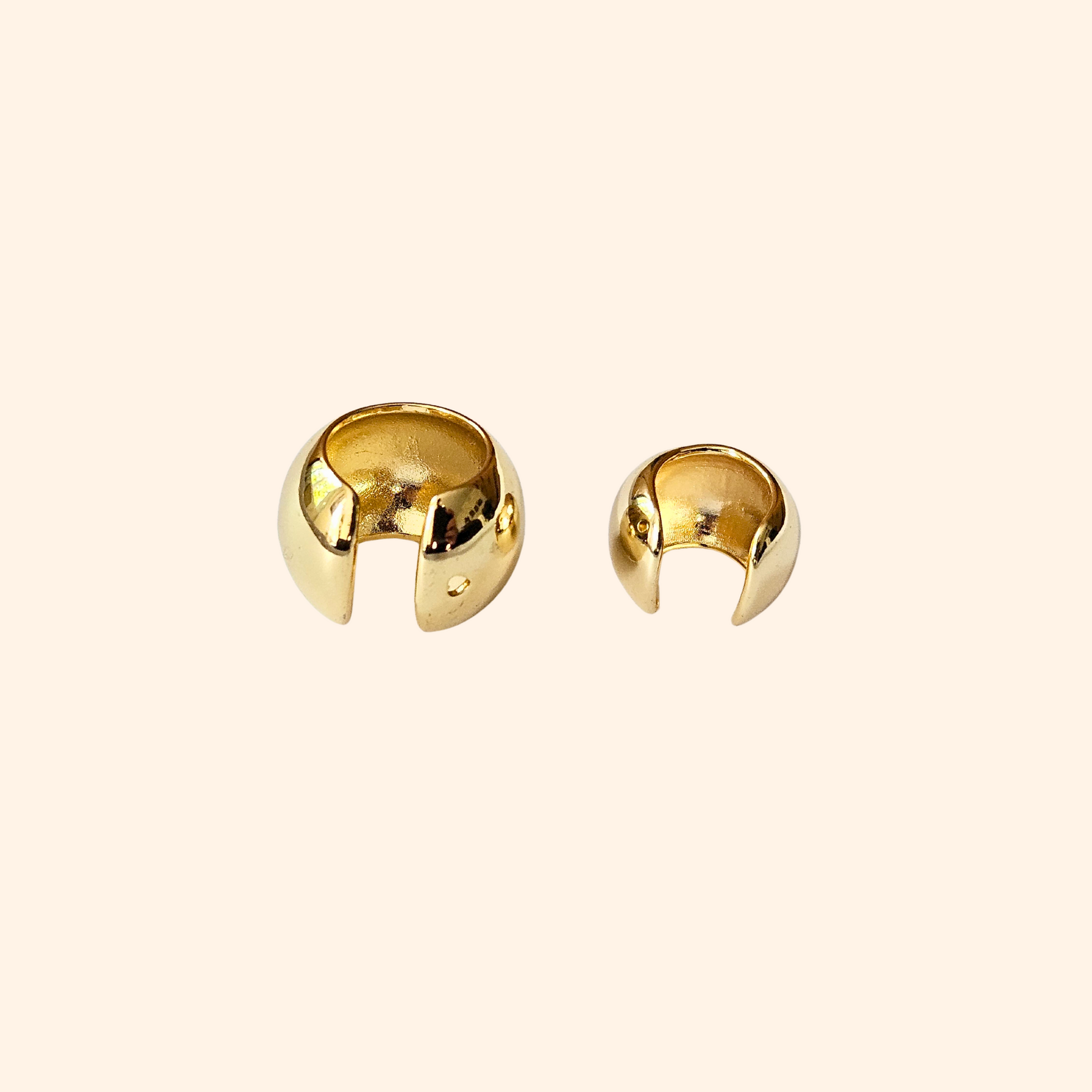 The Dome Shape Ear Cuff by Roots Jewellery features a shiny, metallic open-ended design, elegantly highlighting its dome style against a plain backdrop. This versatile accessory is perfect for adding an edgy touch to any style, resembling a sleek stainless steel ear cuff.