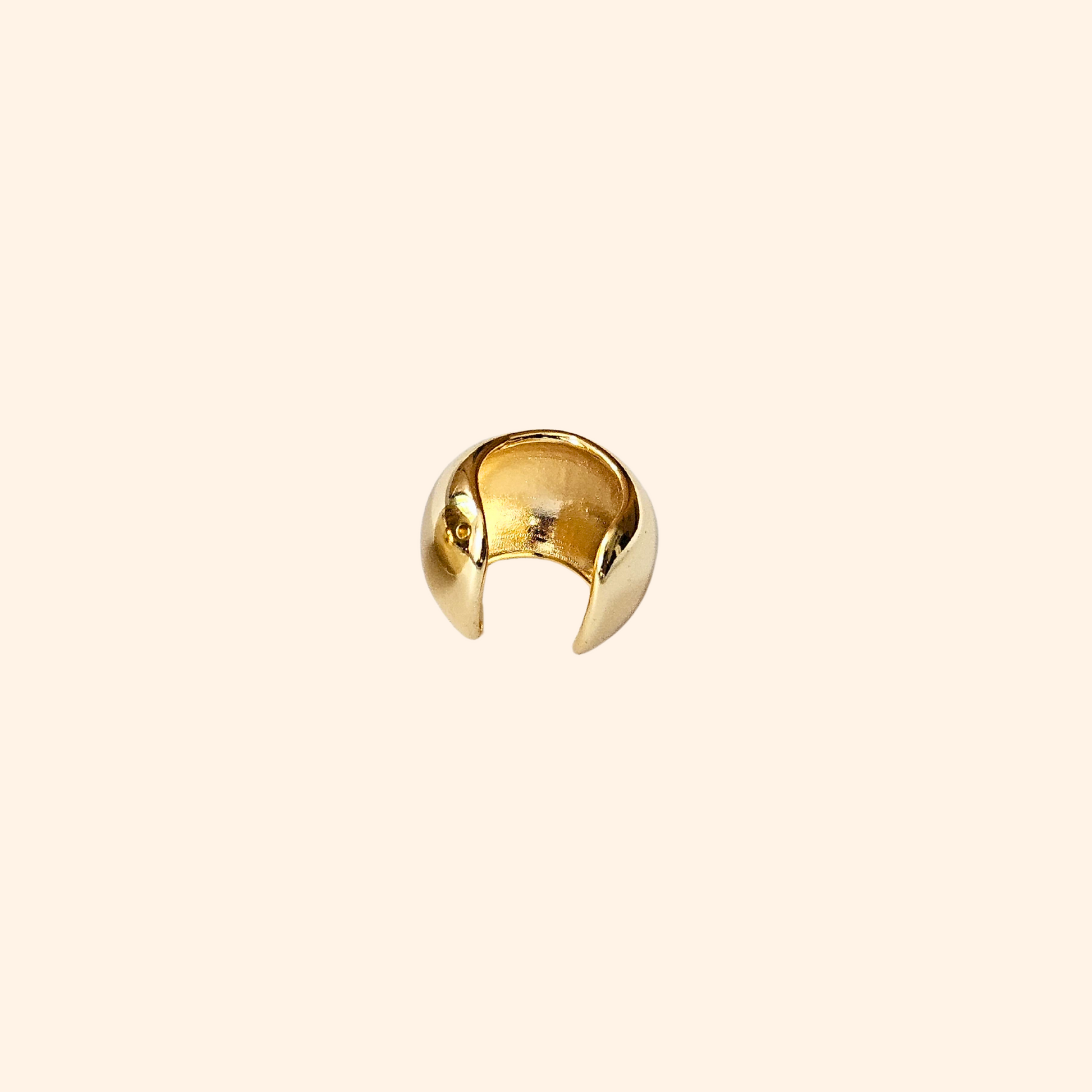 The Dome Shape Ear Cuff by Roots Jewellery features a shiny, metallic open-ended design, elegantly highlighting its dome style against a plain backdrop. This versatile accessory is perfect for adding an edgy touch to any style, resembling a sleek stainless steel ear cuff.