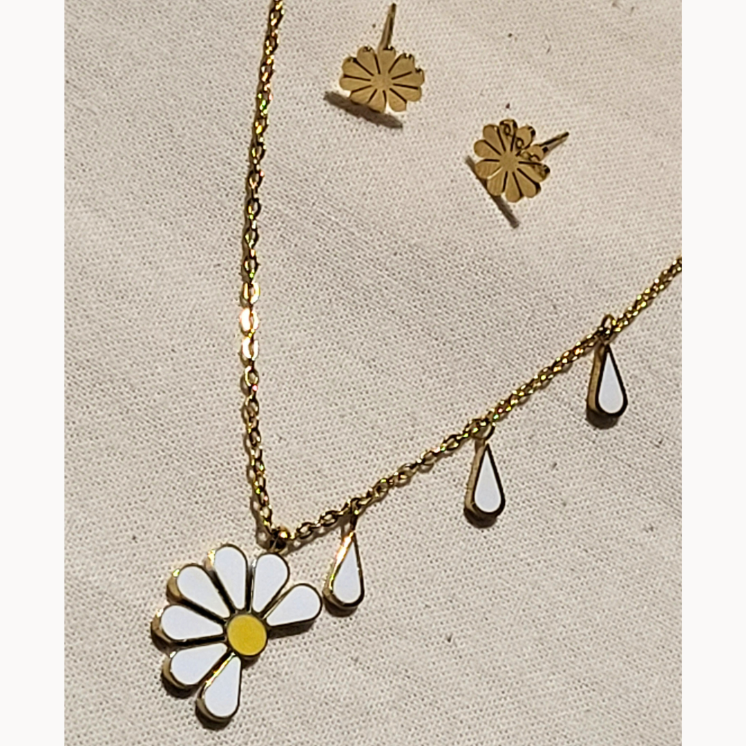 A woman is elegantly dressed in a white top, accessorized with a stainless steel daisy-shaped earring and the Daisy Necklace from Roots Jewellery.