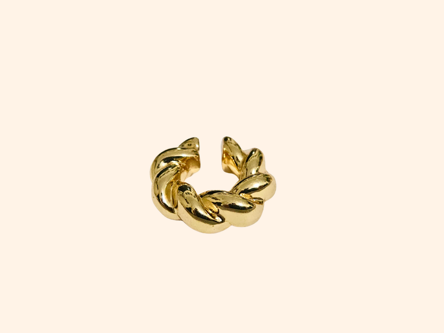 Close-up of the Roots Jewellery gold Spiral Ear Cuff with a sleek braided design, set against a plain, light beige background.