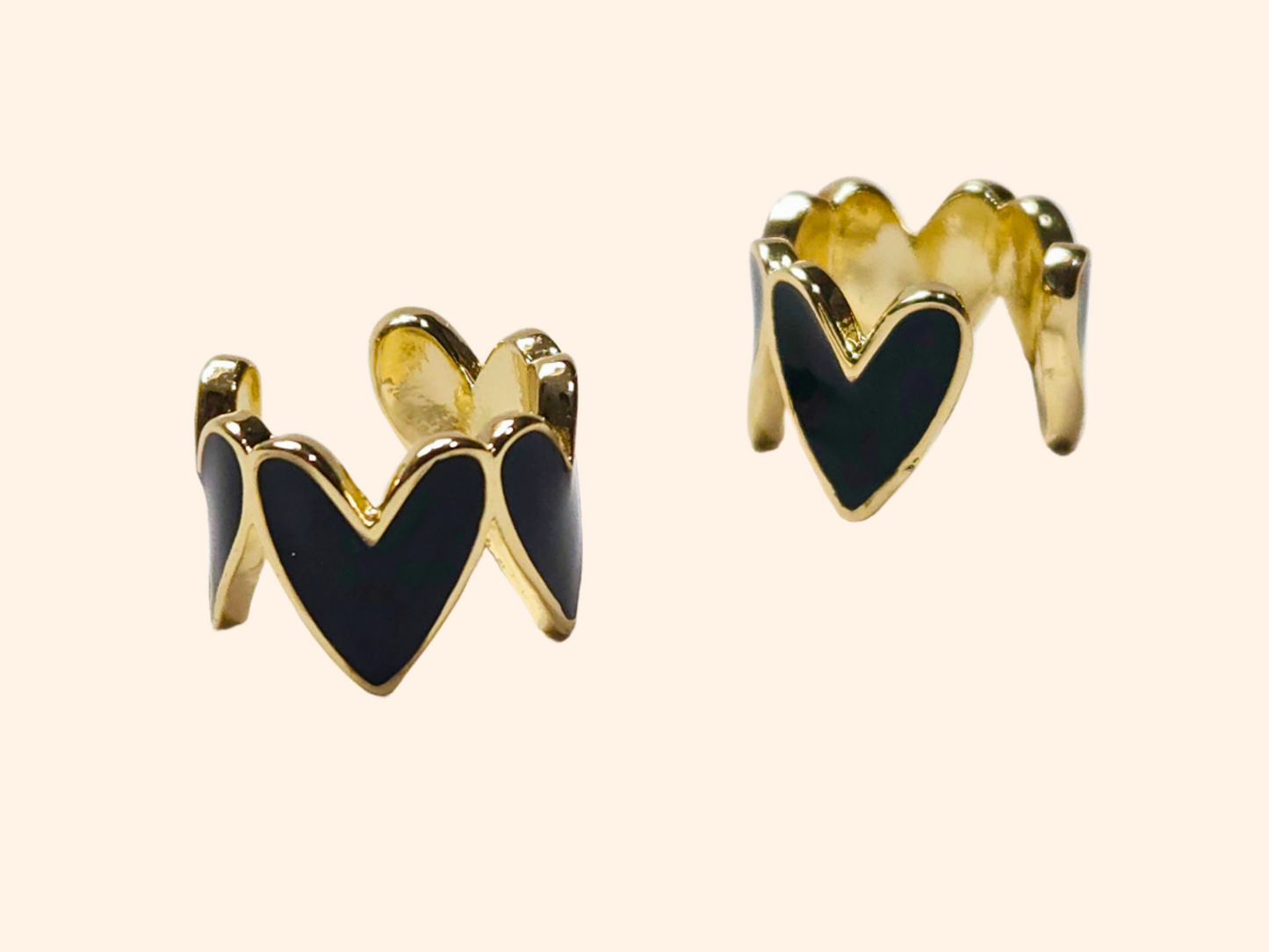 This chic accessory is the Heart-shaped Ear Cuff by Roots Jewellery, showcasing a gold finish with a repeating white heart pattern on a light beige background.