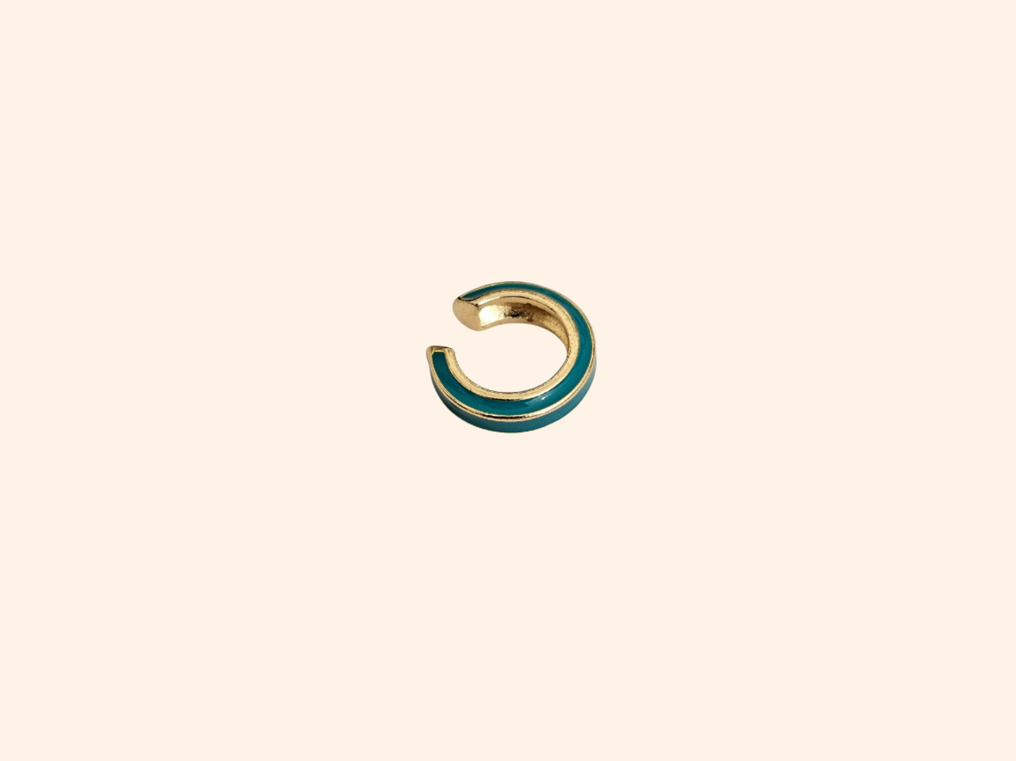 The Single Colour C Shape - Ear Cuff by Roots Jewellery is a small gold and teal ear cuff that elegantly showcases its intricate gold design, set against a beige background, highlighting this exquisite jewelry accessory.