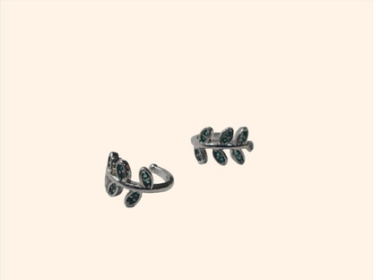 The Leaf - Silver & Green - Ear Cuff by Roots Jewellery, featuring a leaf-shaped design with small emerald green zircons, provides a versatile accessory suitable for any occasion.