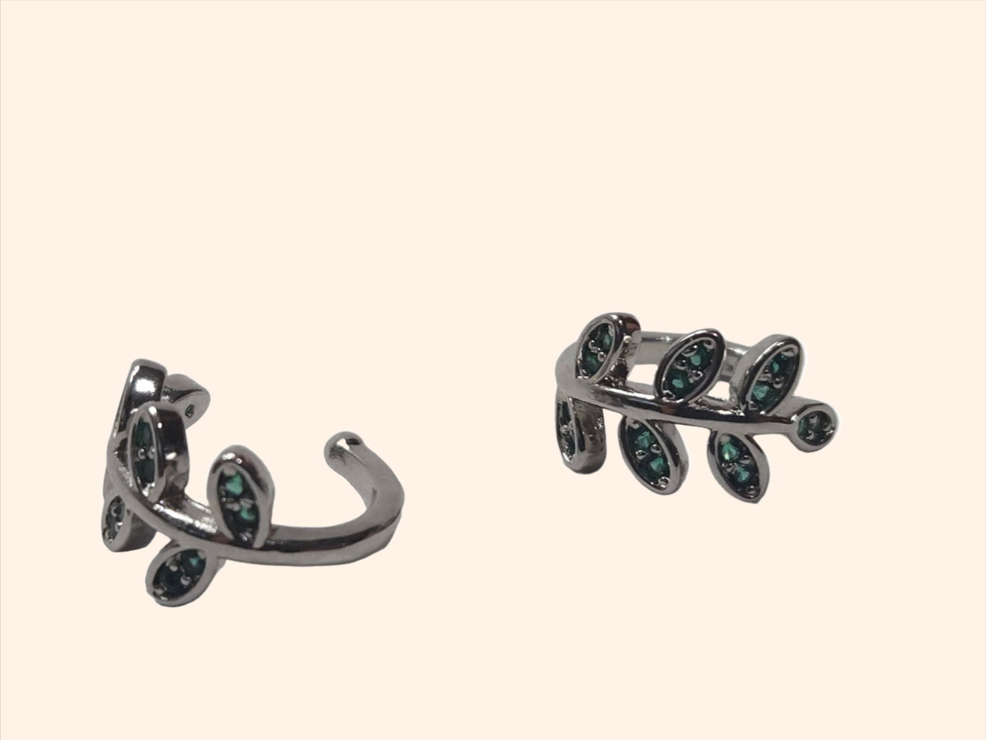 The Leaf - Silver & Green - Ear Cuff by Roots Jewellery, featuring a leaf-shaped design with small emerald green zircons, provides a versatile accessory suitable for any occasion.